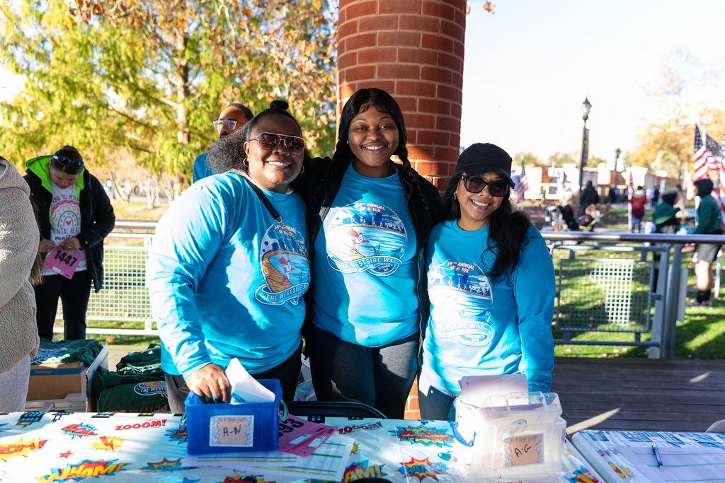 Three smiling participants wearing Westside Way shirts